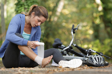 sportwoman bandaging her painful ankle injury outside - obrazy, fototapety, plakaty