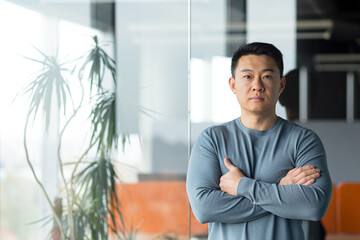 portrait of asian freelance businessman in modern office, man with arms crossed looking seriously at camera - obrazy, fototapety, plakaty