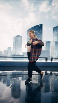 Vertical Screen: Stylish Young Professional Female Dancer Performing a Hip Hop Dance Routine in Front of Big Led Wall Screen with Modern City Skyline with Office Skyscrapers in Studio Environment.