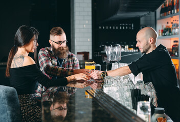The bartender pours cocktails to a young couple in a restaurant.