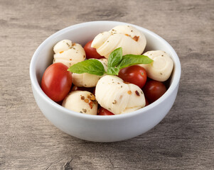 Nozinho or Knot mozzarella, typical brazilian artisanal fresh white cheese with seasonings, basil and cherry tomatoes