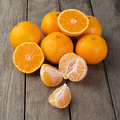 Tangerines with cut fruit over wooden table