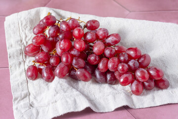 a bunch of red grapes is lying on a linen towel. Fresh natural grapes