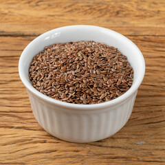 Brown linseed on a bowl over wooden table