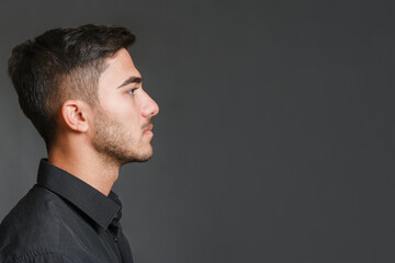 Close-up profile view portrait of young handsome serious guy on gray background. High quality...