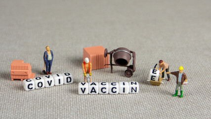 the team of miniature figurines of workers preparing covid vaccine for use, is vaccine developed in...