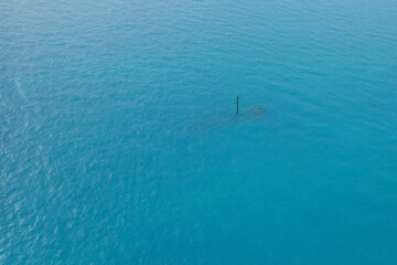 Aerial view of shipwreck in the ocean with mast sticking up