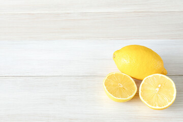 Whole and cut ripe lemons on white wooden background. Copy space