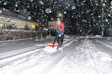 Elderly man with a shovel in his hands clears the street after a heavy snowfall. Man at seasonal...