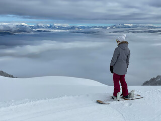 COPY SPACE: Woman observes the foggy valley before snowboarding in backcountry.