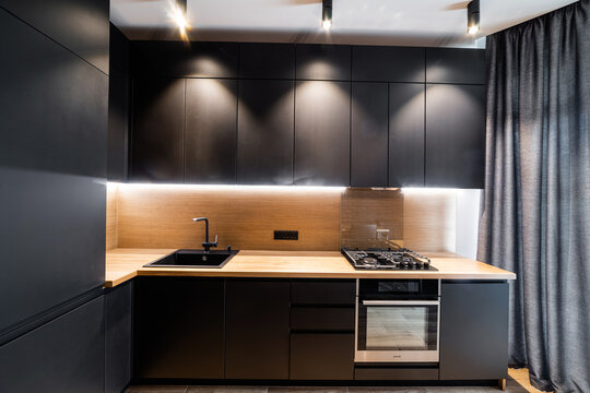 Stylish modern designer black kitchen with spot lighting and wood countertop
