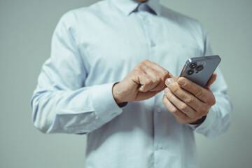 businessman holding a smartphone in his hand on a gray background. business concept