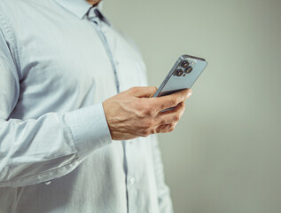 man holding a smartphone in his hand on a gray background. business concept