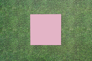 A pink copy space on artificial grass background. Concept for Valentines card, advertisement or web banner for products. Minimal spring or summer design. Flat lay.