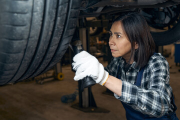 Obraz na płótnie Canvas Qualified female mechanic tackling a technical car issue