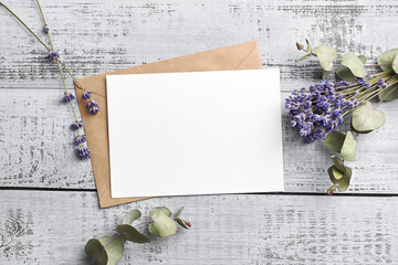 Greeting or invitation card mockup with dry lavender and eucalyptus plants on wooden background