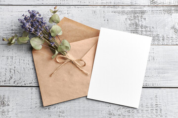 Greeting or invitation card mockup with dry lavender and eucalyptus plants on wooden background