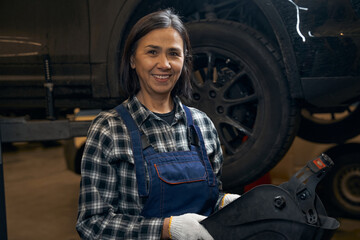 Amicable lady enjoying working as a car technician
