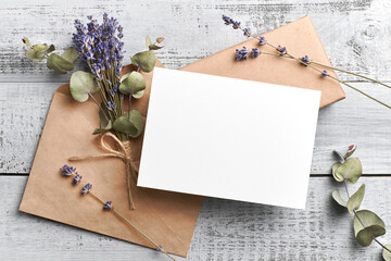 Naklejka na ściany i meble Wedding invitation or greeting card mockup with lavender and eucalyptus flowers on wooden background