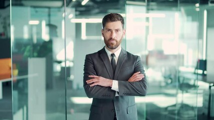 portrait successful confident Caucasian bearded male office worker standing and looking at camera in formal suit indoors. face of a business man or entrepreneur employee crossed arms. In modern glass
