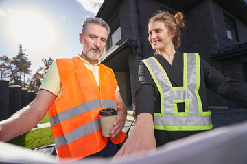 Satisfied construction engineer pointing out something on drawings to worker