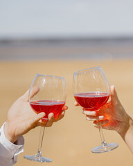 a couple of a man and a woman walk along the beach and have a picnic on the sand on the seashore or ocean. beautiful and young European man and woman on a romantic walk in nature drink wine and enjoy