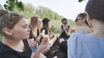 Girlfriends eat ice cream at a picnic outside the city.