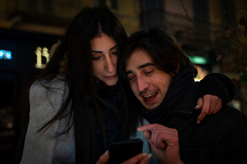 happy young couple is chatting on smartphone outdoors