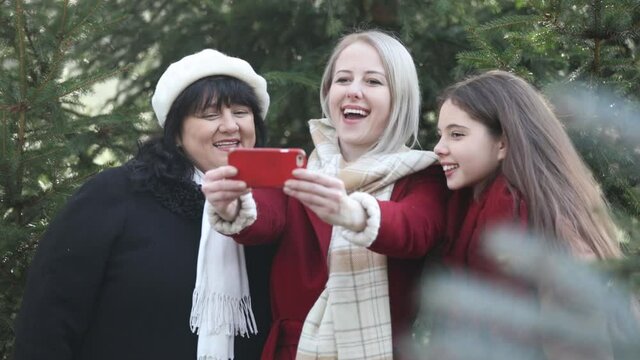 Mother with two daughters take a selfie near pine tree