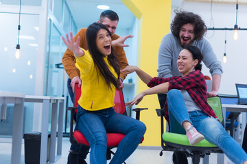 Young business people ride chairs in the office