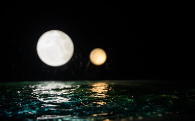 Romantic and scenic panorama with full moon on sea to night. Table decoration with moon miniature and water.