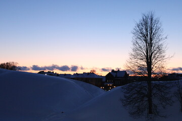 sunset in winter,  view on hills covered by snow and homes on horizon 