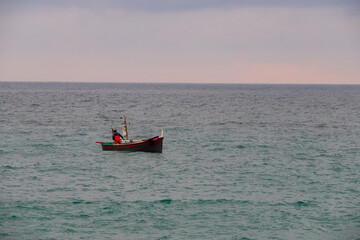 a fisherman and his boat along the coast of the Ligurian Sea, while he is starting to fish