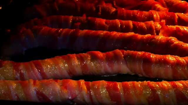 Opening oven to reveal sizzling extra long pigs in blankets bacon wrapped roasted party food close up track right
