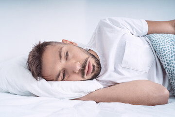 Stressed and depressed man lying in the bed. Man feeling bad, desperate and helpless