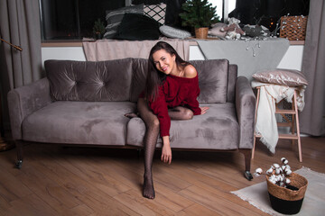 Obraz premium a girl in a red sweater on the sofa in a room with a Christmas decor.