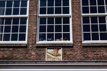 Fototapeta na wymiar Traditional Dutch Tile Work from the Renaissance Era beneath Windows on a Brick Row House in Amsterdam, Netherlands 