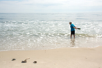 boy plays with ocean waves. Summer family vacation on beach. Outdoor family fun