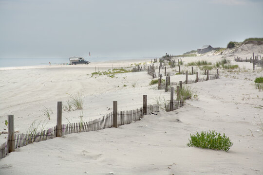 Sand Dunes With Green Grass And A Wooden Fence With Ocean In Background. Seaside Heights, NJ.