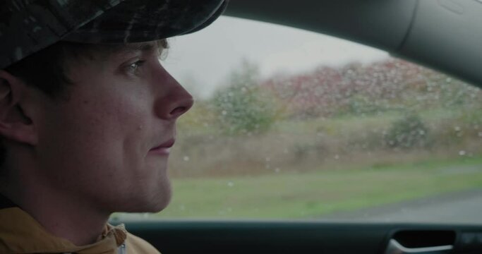 Young Man Turns and Searches for a Parking Spot in The Rain - Handheld Close Up