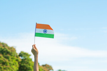 hand holding India flag on blue sky background. Holiday of India republic Day, happy Independence...