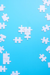 Fototapeta premium Group of white puzzle jigsaw pieces on blue background. Concept of solutions, mission, success, goals, cooperation, partnership, strategy and puzzle day