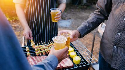 Friends and bbq party hold a plastic beer mug to celebrate the New Year holidays.