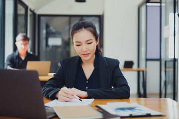 Business woman working to analyze technical price graph and indicator at office with businessman working on background. account or saving money or insurance concept.