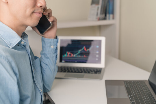 Young businessman, trader, investor using smartphone, laptop with stock market, Cryptocurrency graph chart for investing, trading as stock market, Cryptocurrency as Bitcoin. Trading, investing concept