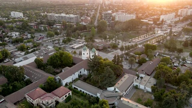 Aerial view of the church of Los Dominicos approaching its two distinctive towers with green domes at sunset - crane shot