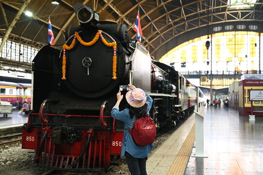 At Hua Lamphong Station Tourists wearing denim shirts, carrying a red backpack, use mobile phones to take pictures of the impression of a vintage steam locomotive train 850,Thailand, 