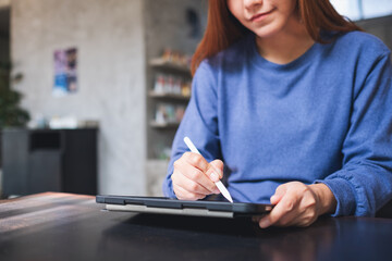 Closeup of a young woman using smart pen technology for working and writing on digital tablet screen
