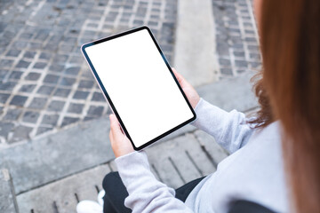Mockup image of a woman holding digital tablet with blank white desktop screen in the outdoors