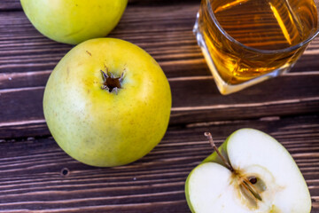 Green apples and glass with apple juice on wooden background